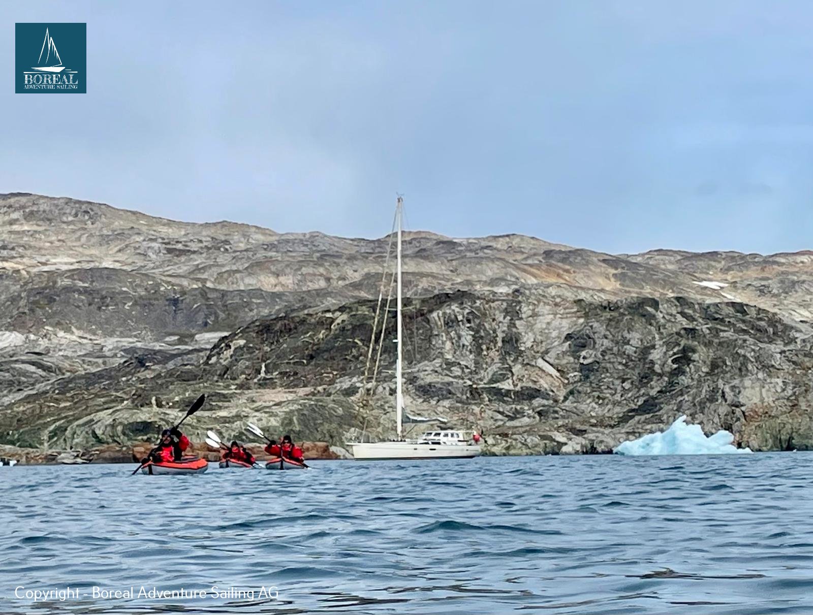Sail & Kayak, East Greenland: kayakers paddling near the anchored expedition yacht and an iceberg