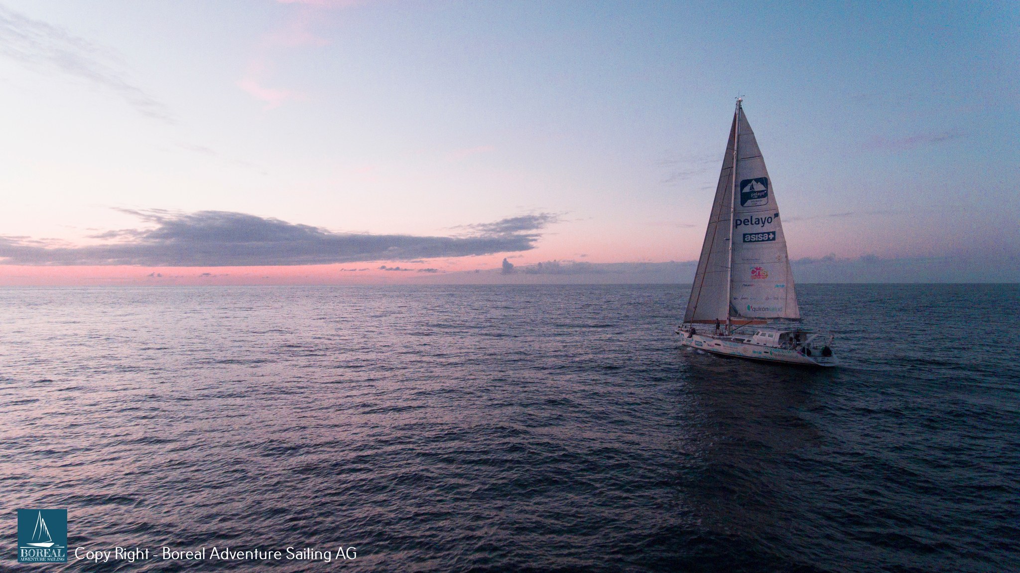 Offshore Sailing: drone view of the yacht under full sail on a calm sea at sunset