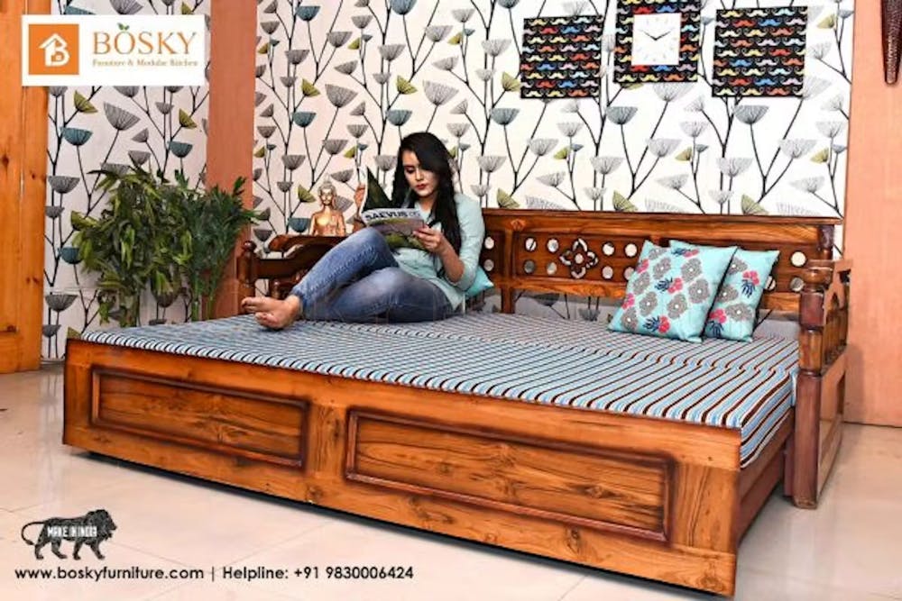 Photo of a lady reading magazine on a solid wood sofa cum bed