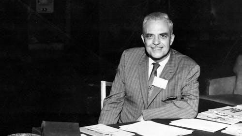Milton Erickson at a table with papers