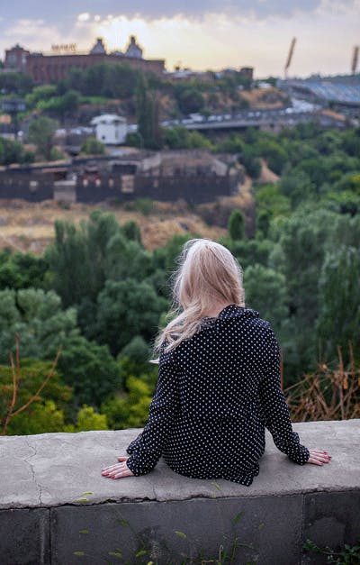 woman sitting on wall overlooking field