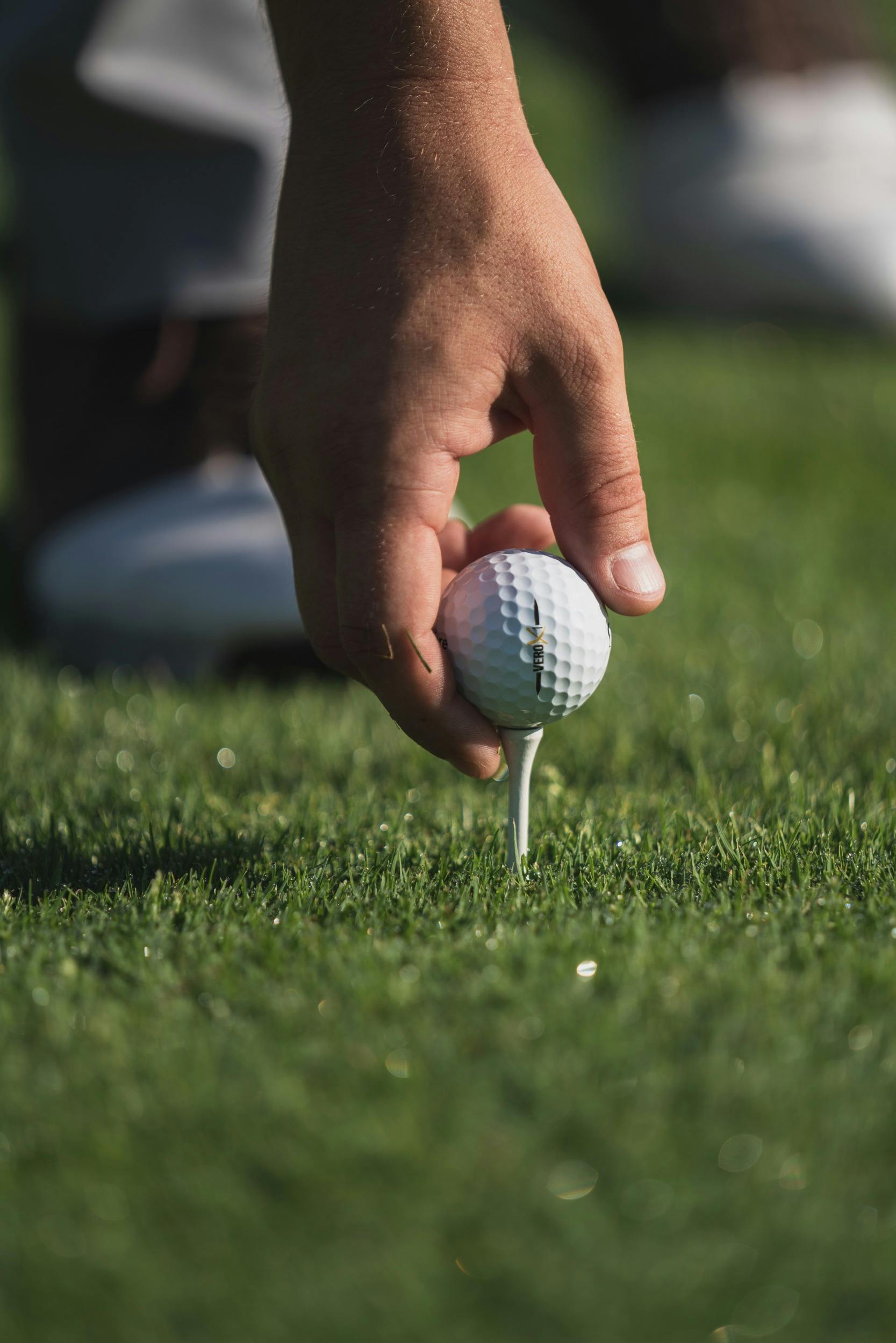 A hand placing golfball on the ground