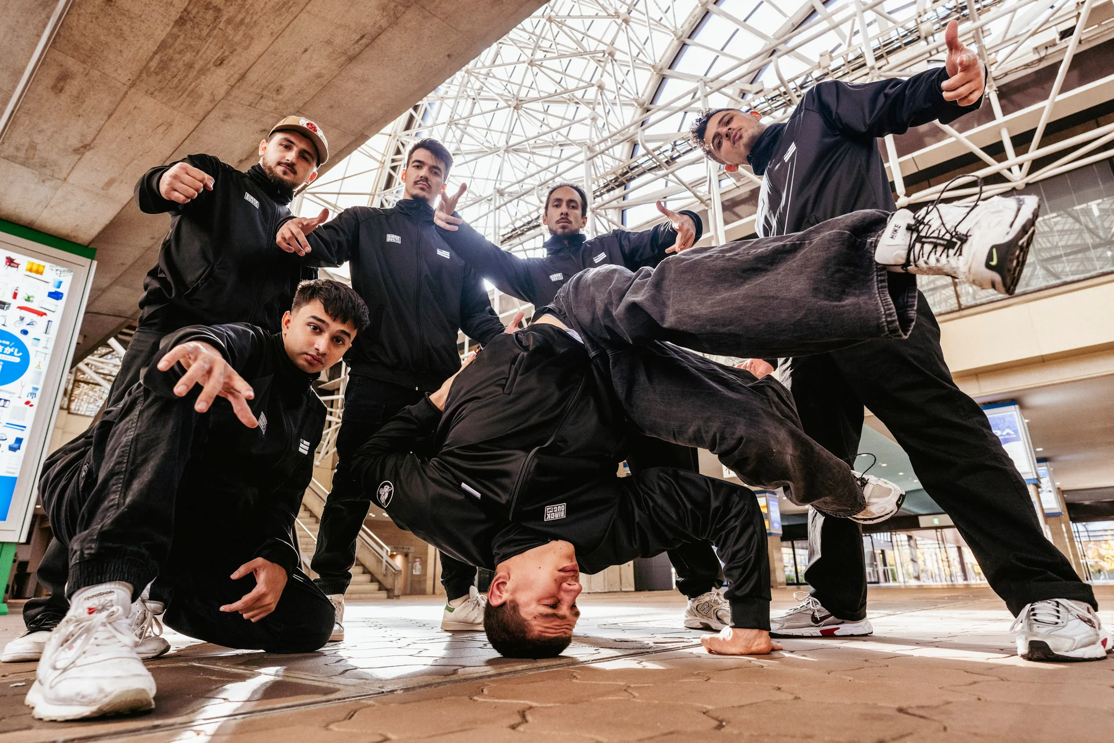 Freeze au sol entouré du crew, compo dynamique remarquable