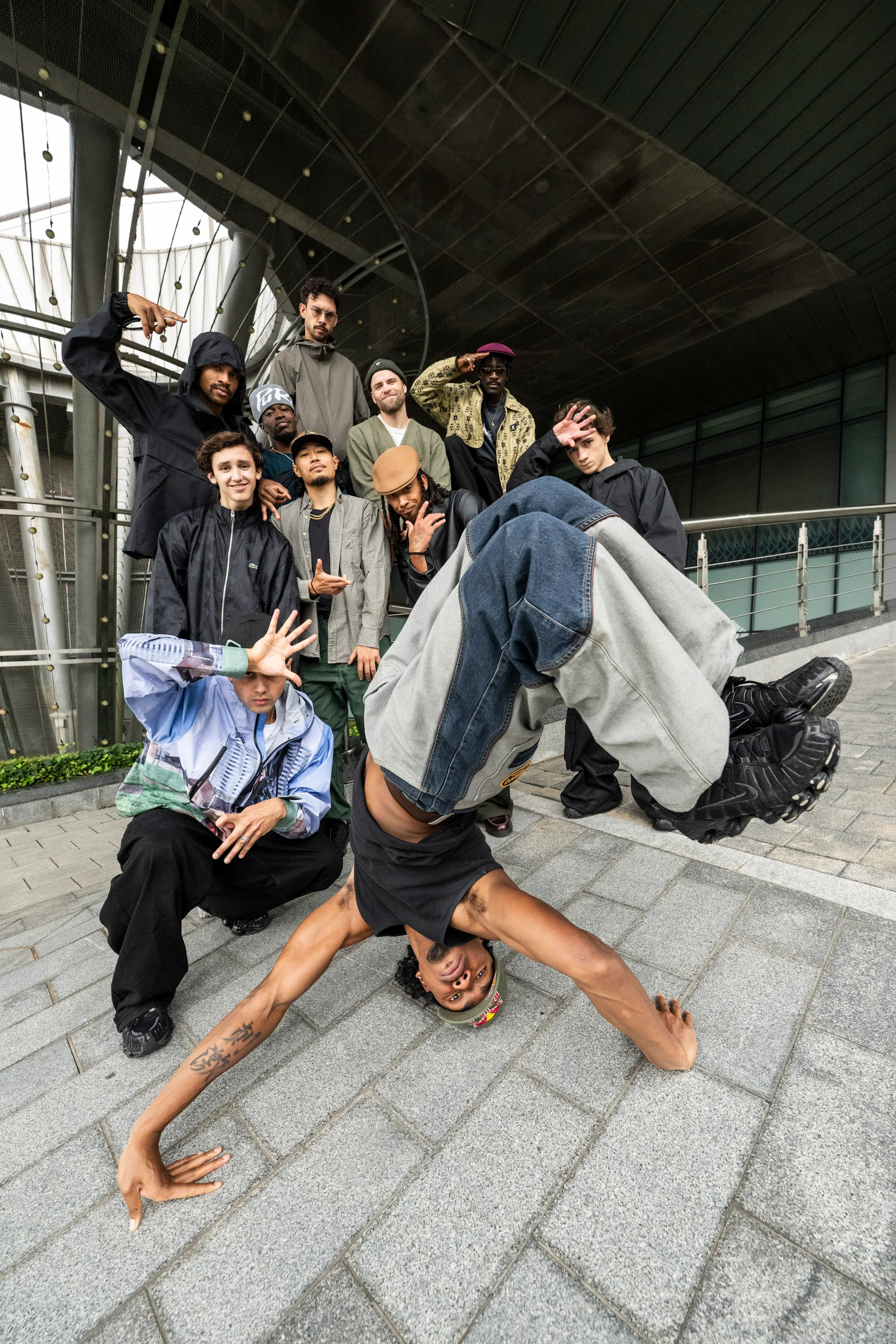 Bboy headspin tête au sol jambes en V, crew pose derrière sous arche en verre, ultra dynamique