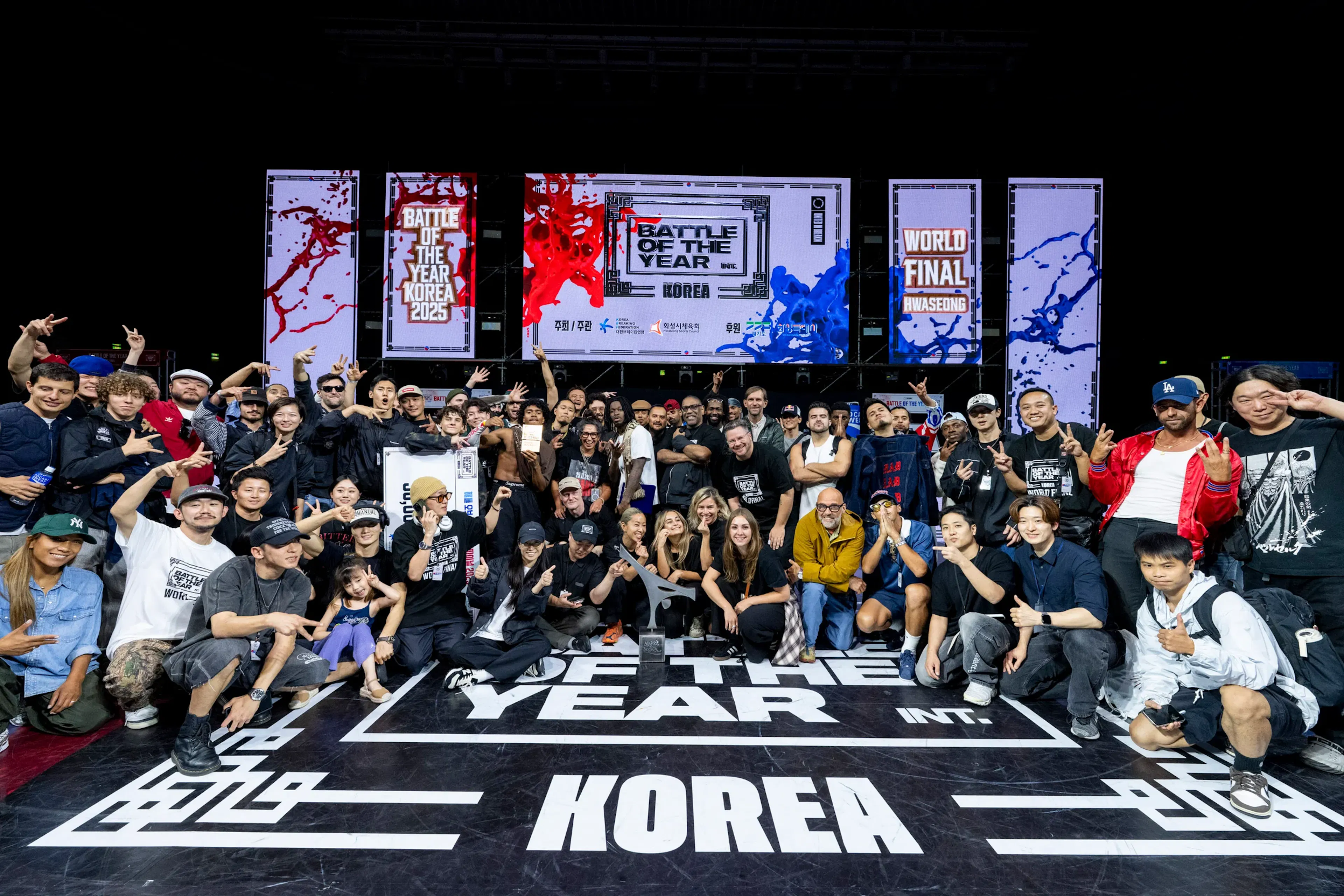 Photo de groupe géante BOTY Korea 2025 finale, tous staff & crews accroupis devant écrans — mémoire collective