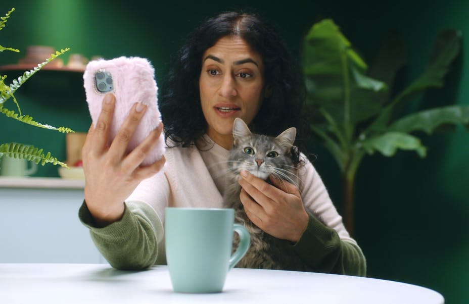 Woman holding cat and phone