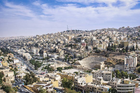 Aerial view of the rooftops of Amman, Jordan, with white clouds in the sky