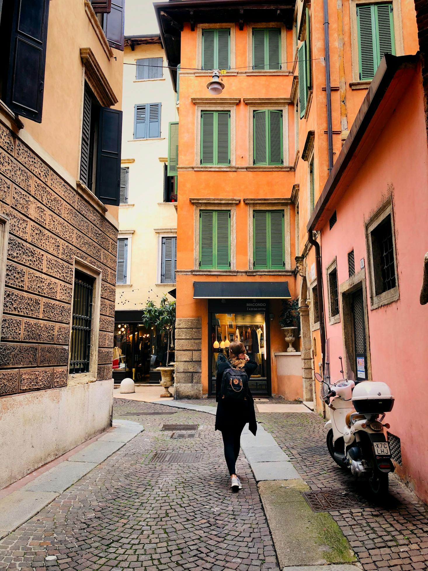 A person walking to their motorcycle on a Verona street