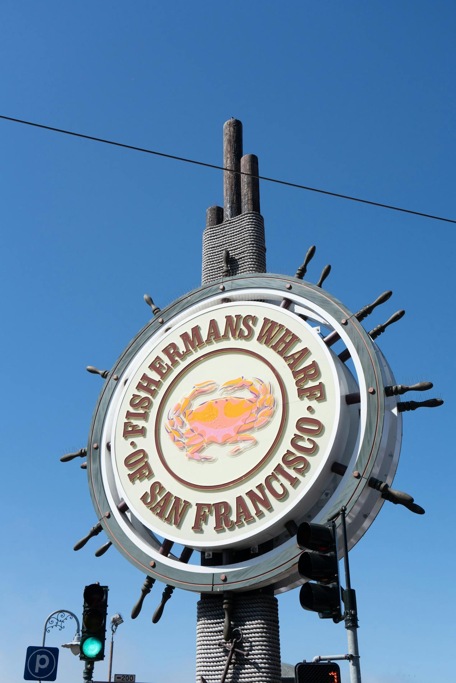 A large sign with a crab on it in the shape of a ship's steering wheel at Fisherman's Wharf in San Francisco