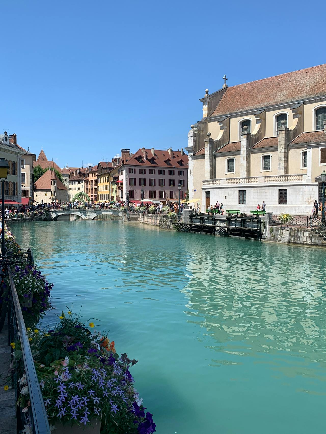 A white building sits on the canal in Annecy, France A white building sits on the canal in Annecy, France