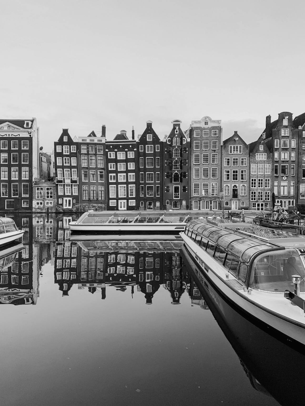 Boats reflecting an Amsterdam canal near luggage storage services