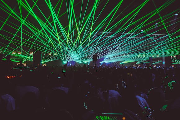 Green and blue lights illuminating the sky above a crowd at a festival