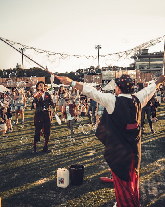 Two entertainers creating bubbles while surrounded by people