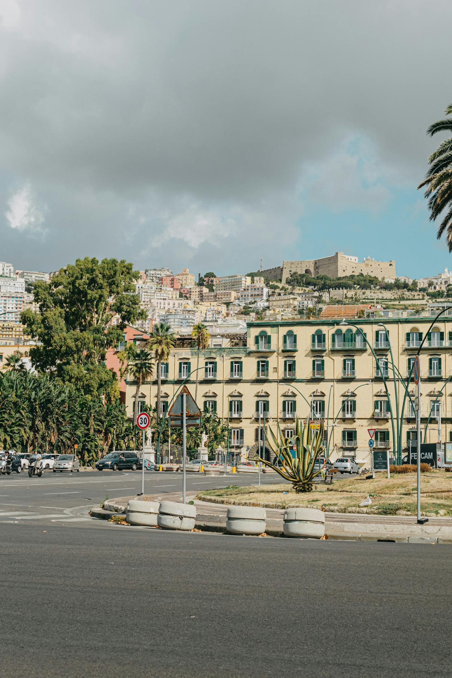 Dark clouds over a light yellow historic building in Naples