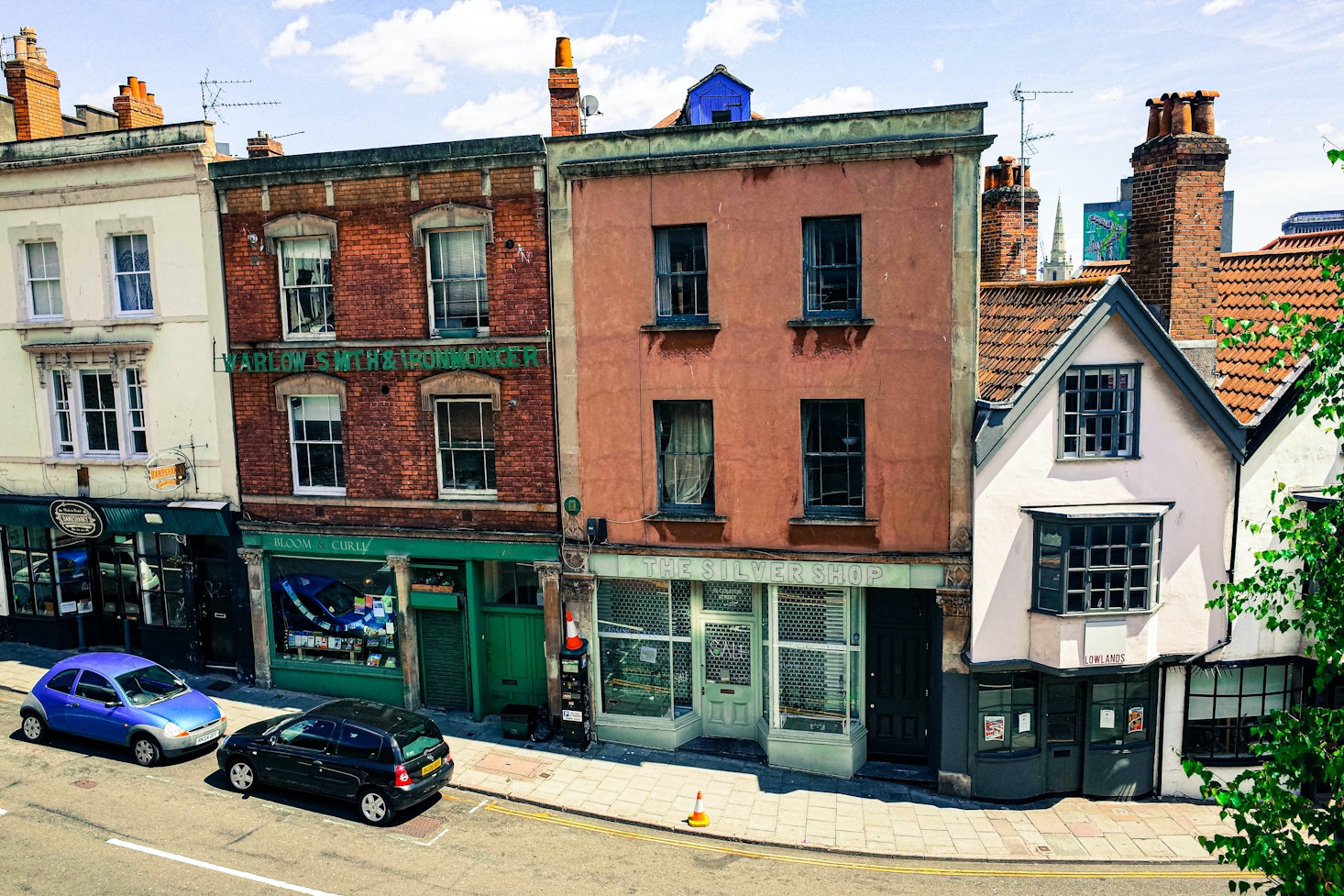 Street view of Bristol vintage shopfronts, including 'The Silver Shop,' with cars parked along the road