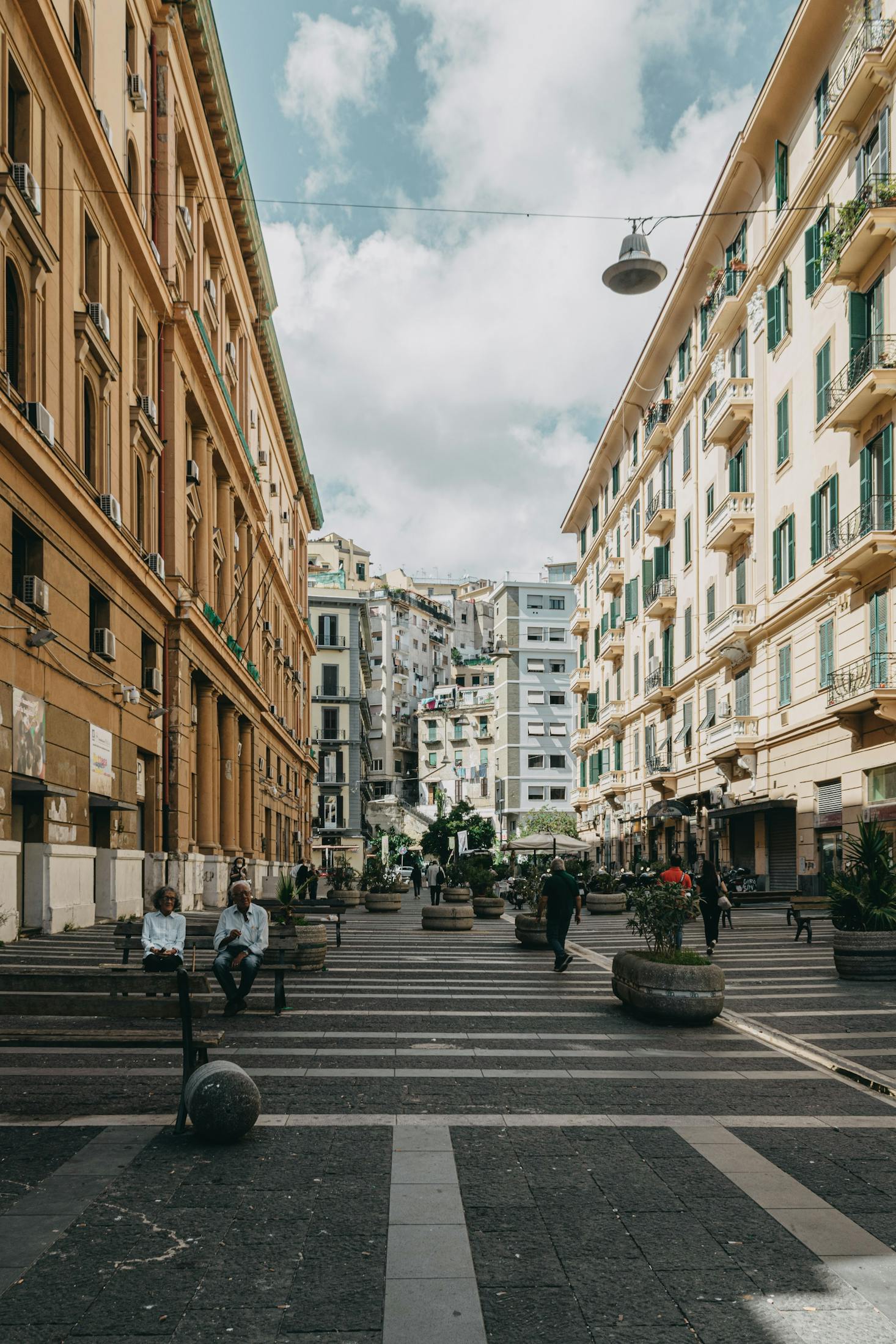 A pedestrianized street in Naples during the day flanked by historic buildings