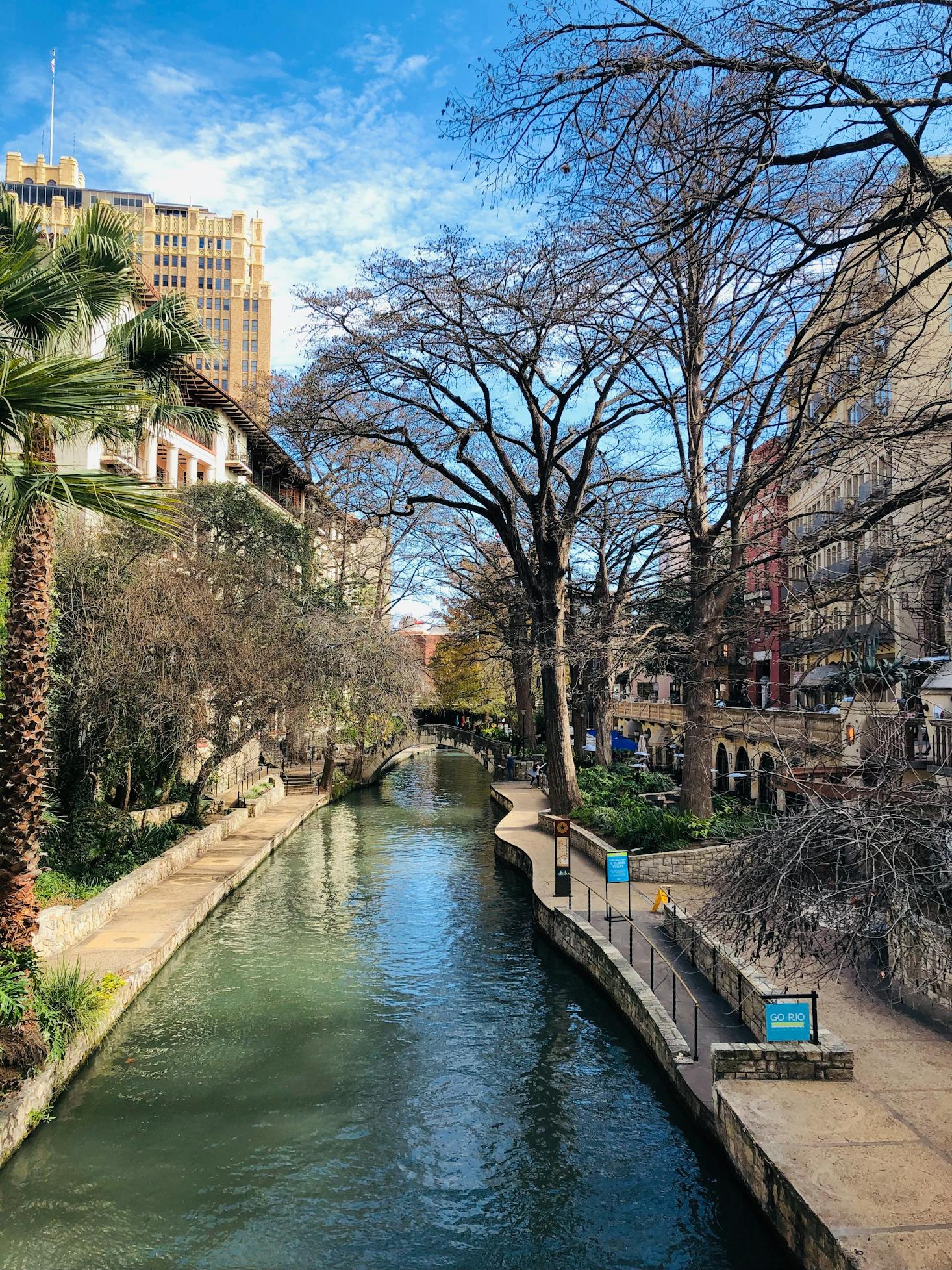 Cement buildings, trees and walkways line a waterway in San Antonio, Texas