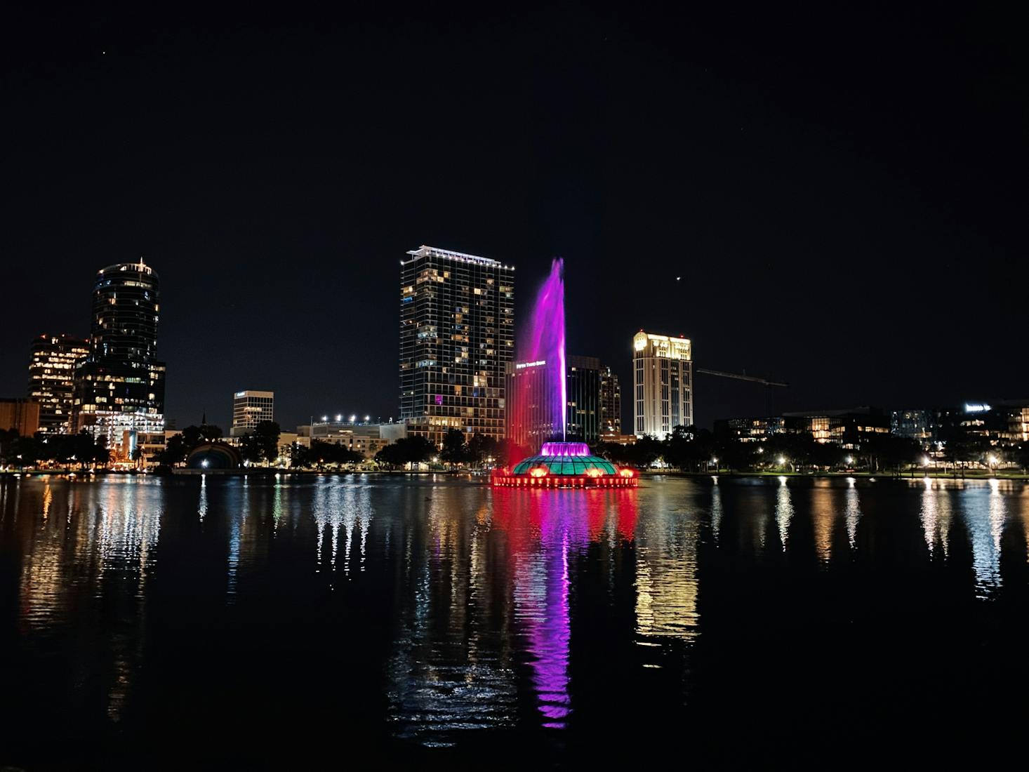 A boat on the water with purple lights in Orlando at night