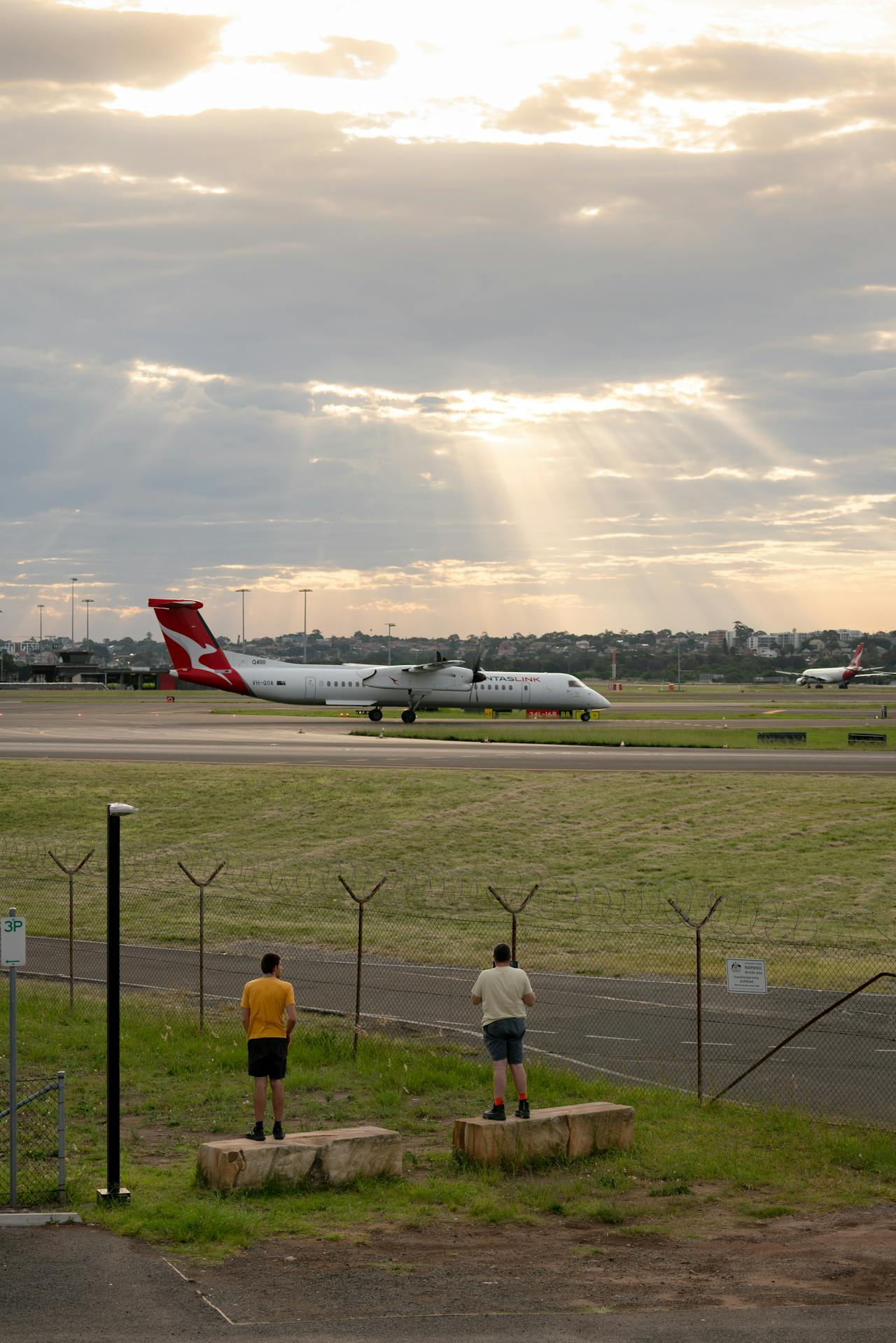 Plane on the runway at Sydney Airport with the sun peeking through the clouds