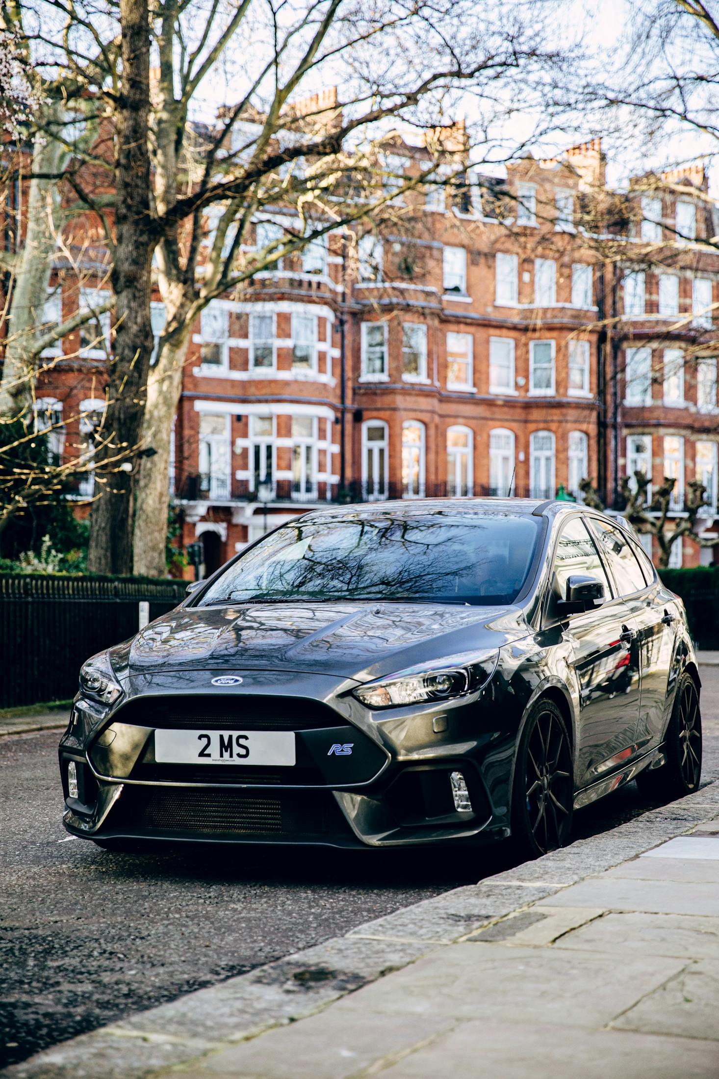 A black car parked in Knightsbridge with brown brick buildings behind it