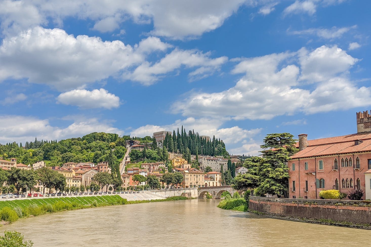 A brown river flowing through Verona on a sunny day
