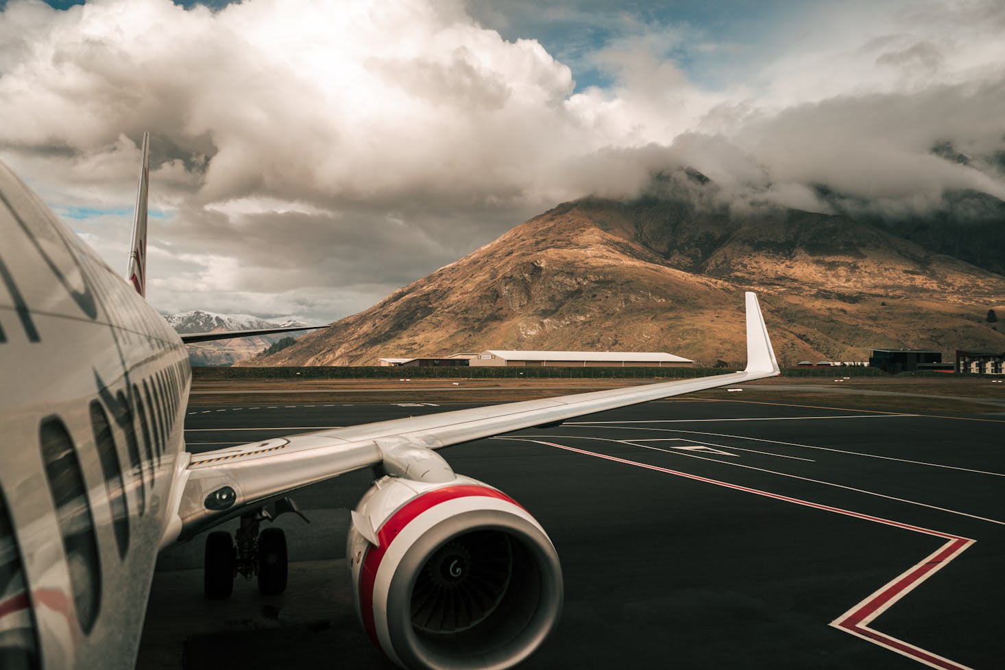 A plane in the sky with a view back to Queenstown Airport, New Zealand