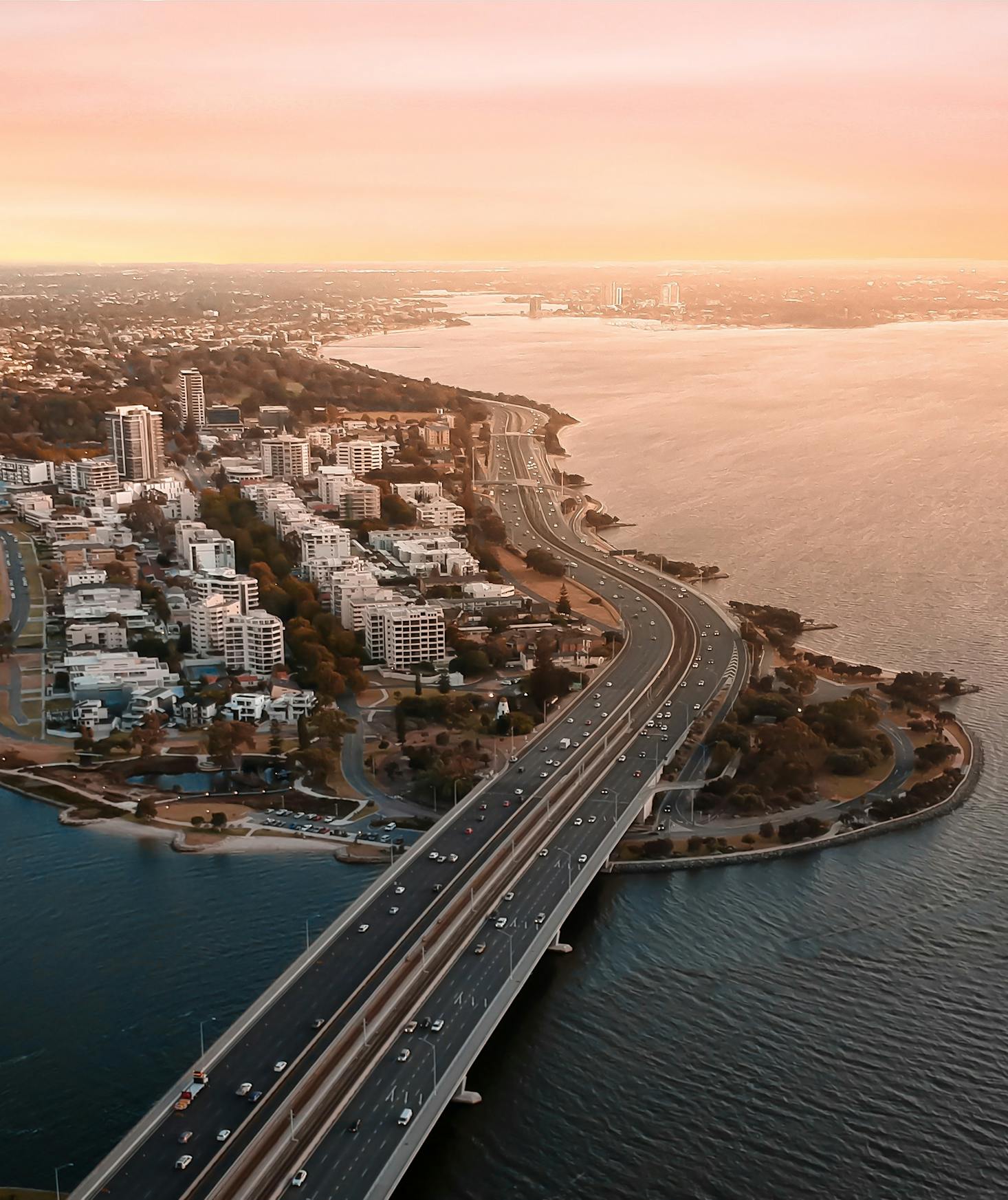 Busy highway leading into the shoreside city of Perth, Australia with sunset in background