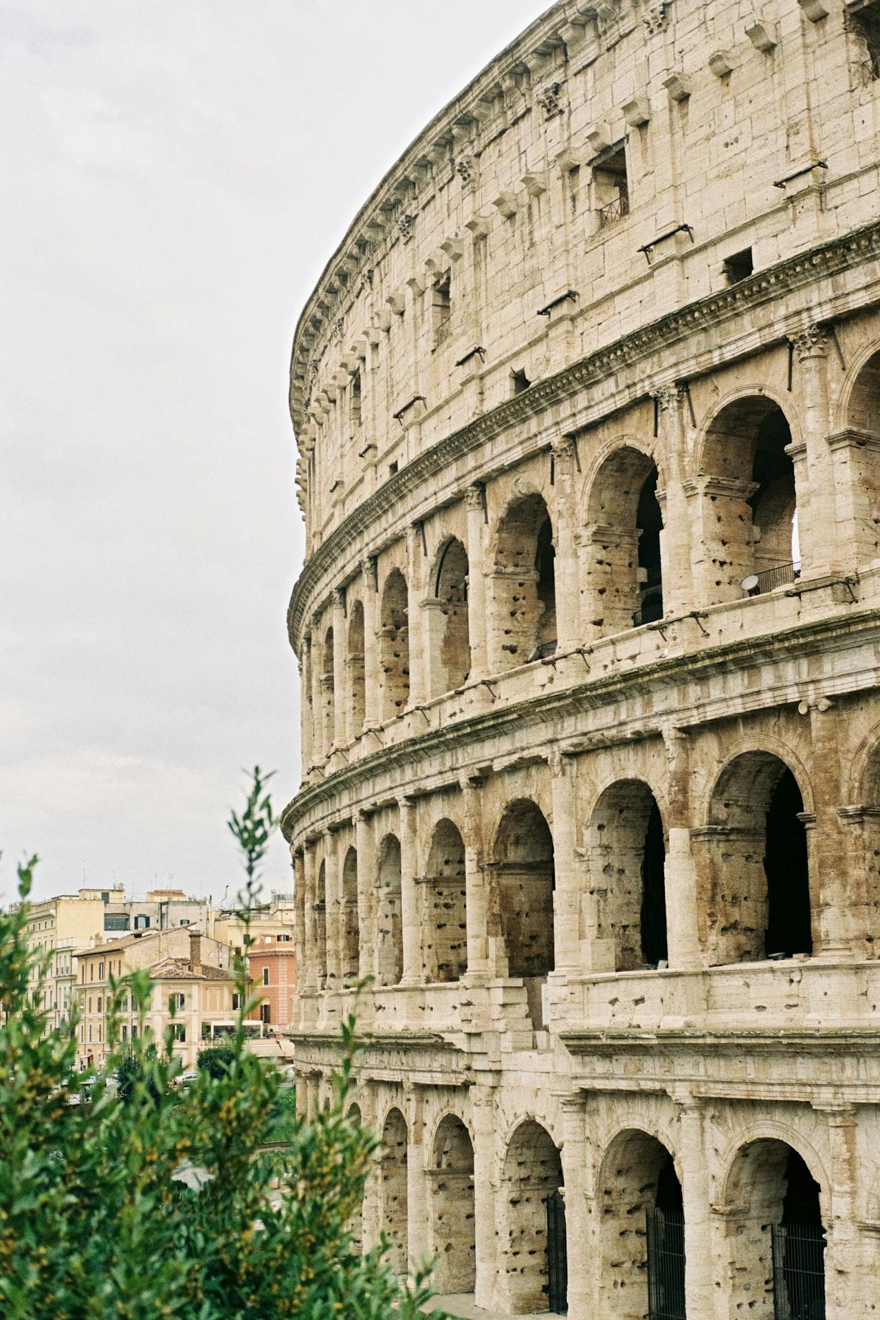 An exterior view of the off-white exterior of Rome's Colosseum on a cloudy day