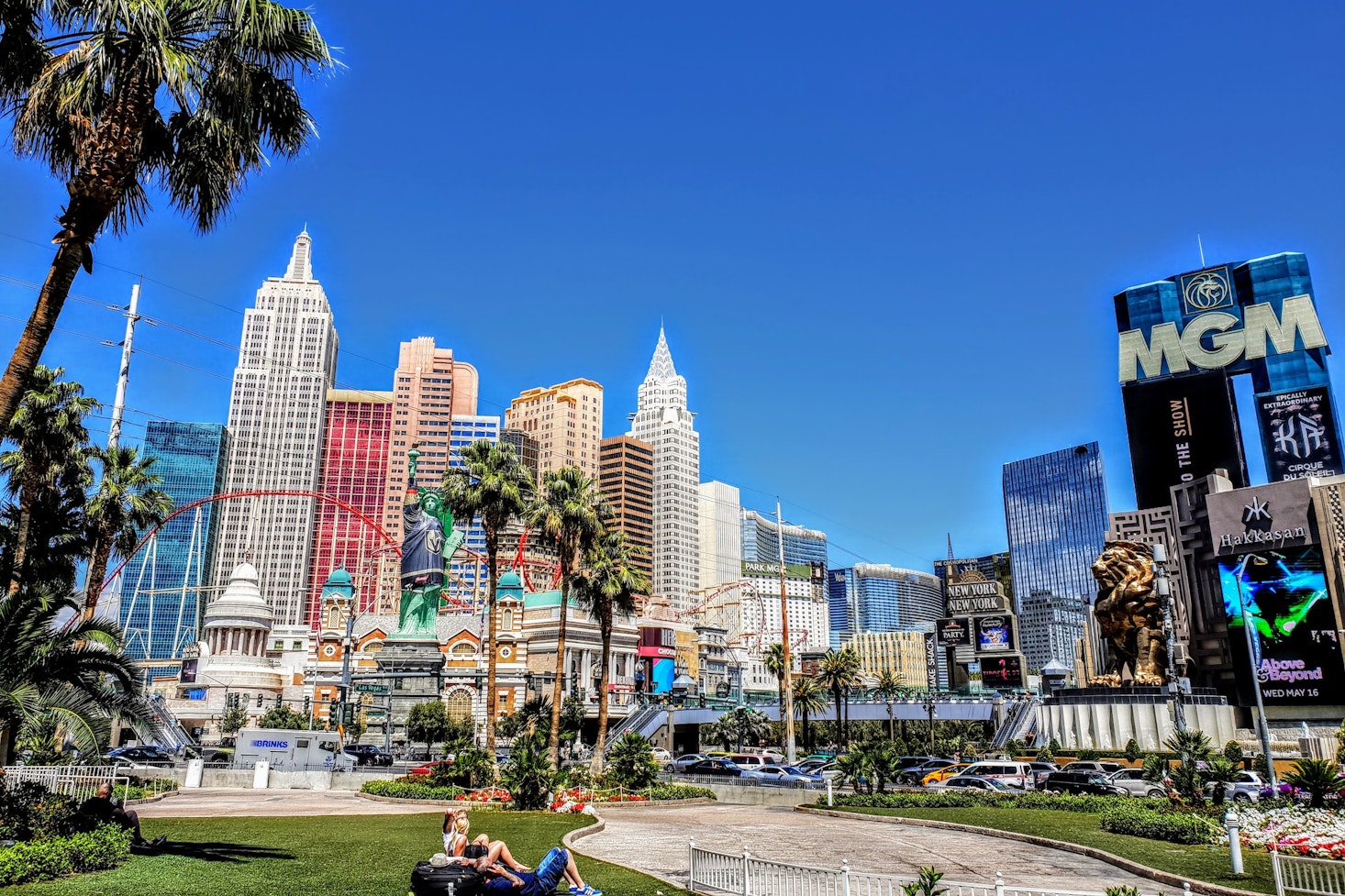 Las Vegas view with palm trees, the MGM and New York-New York Hotels on a sunny day with a colorful skyline and cars