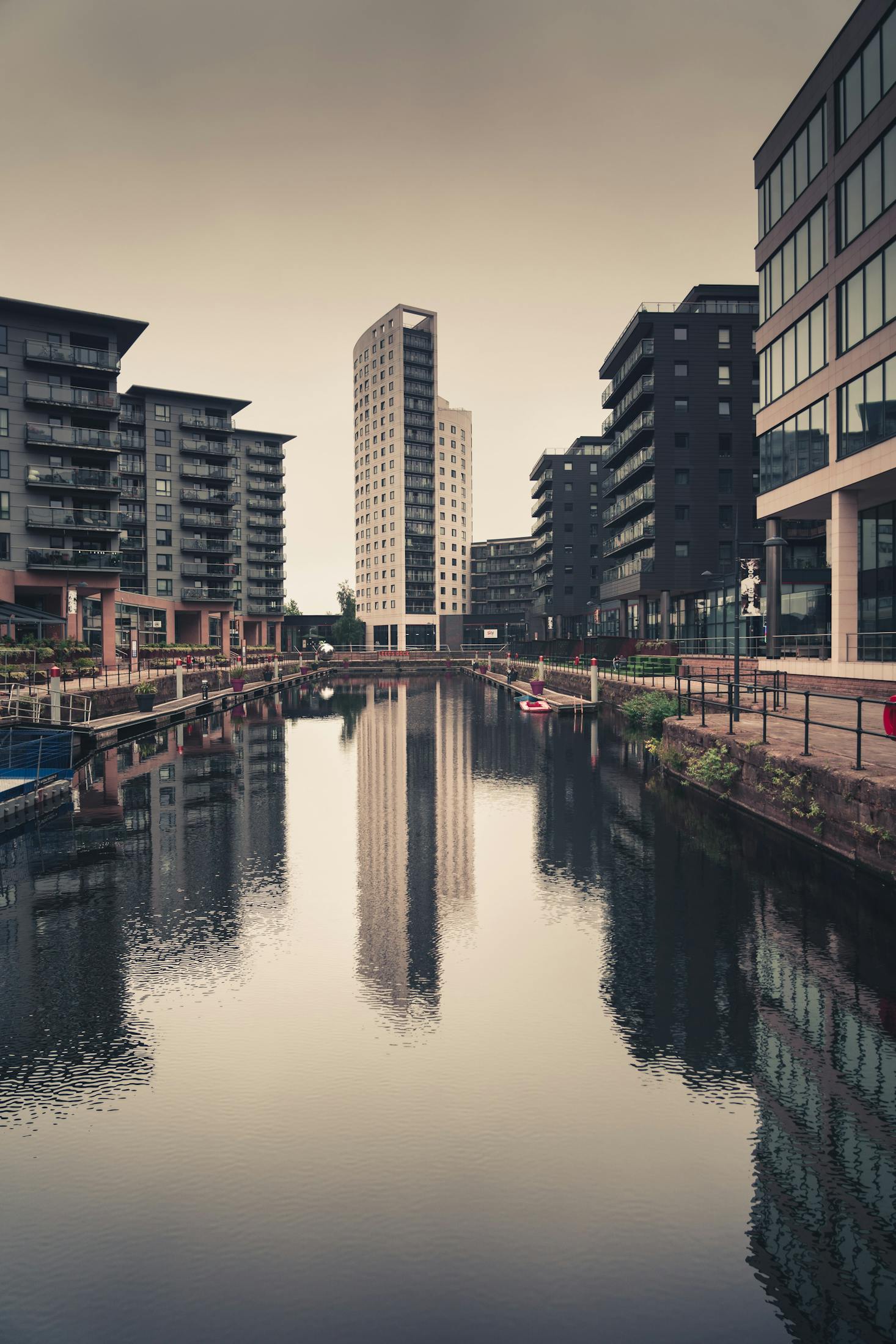 Tall buildings surrounding the River Aire on a cloudy day in Leeds