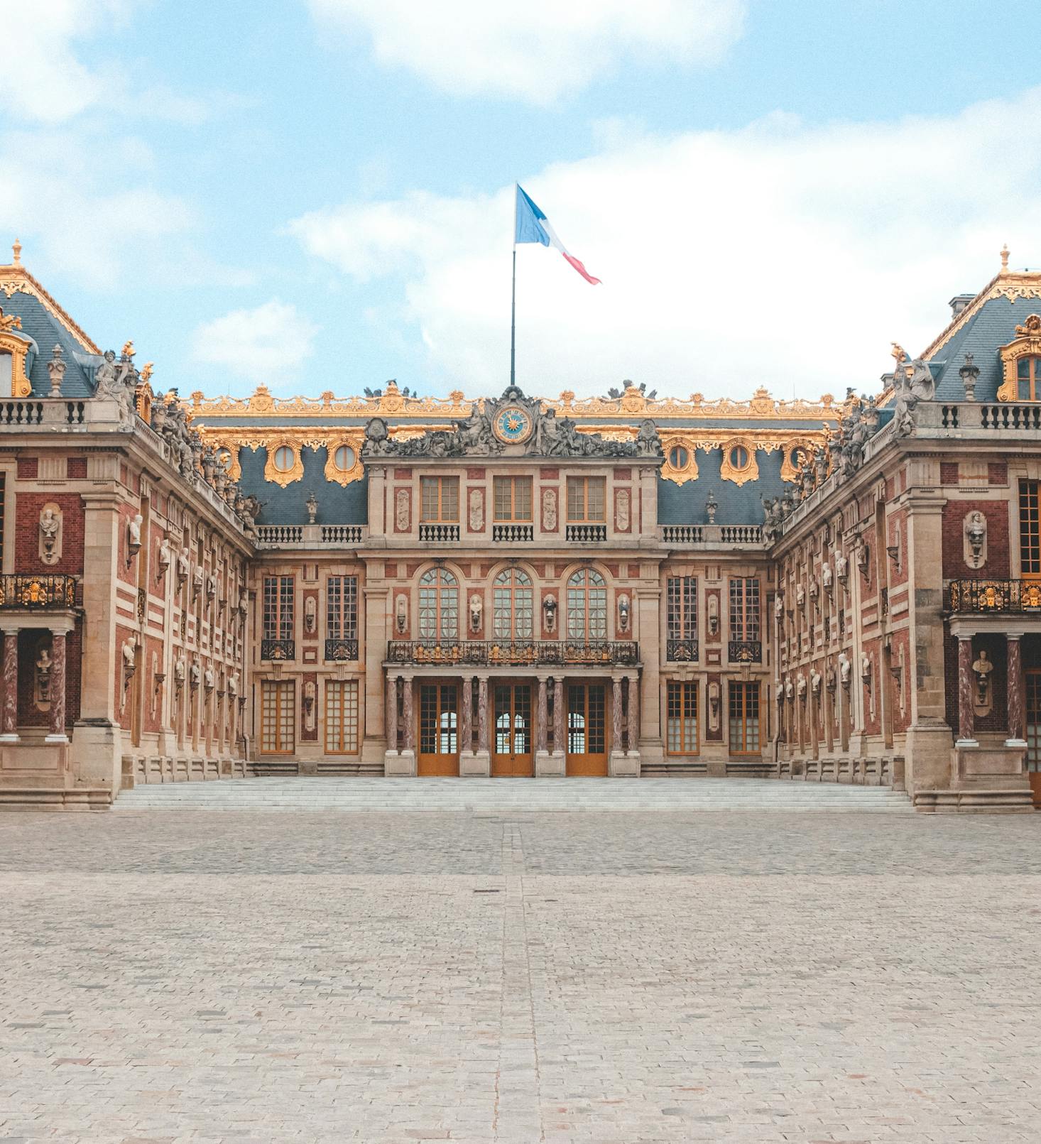 The Palace of Versailles courtyard under a blue sky in Versailles, France