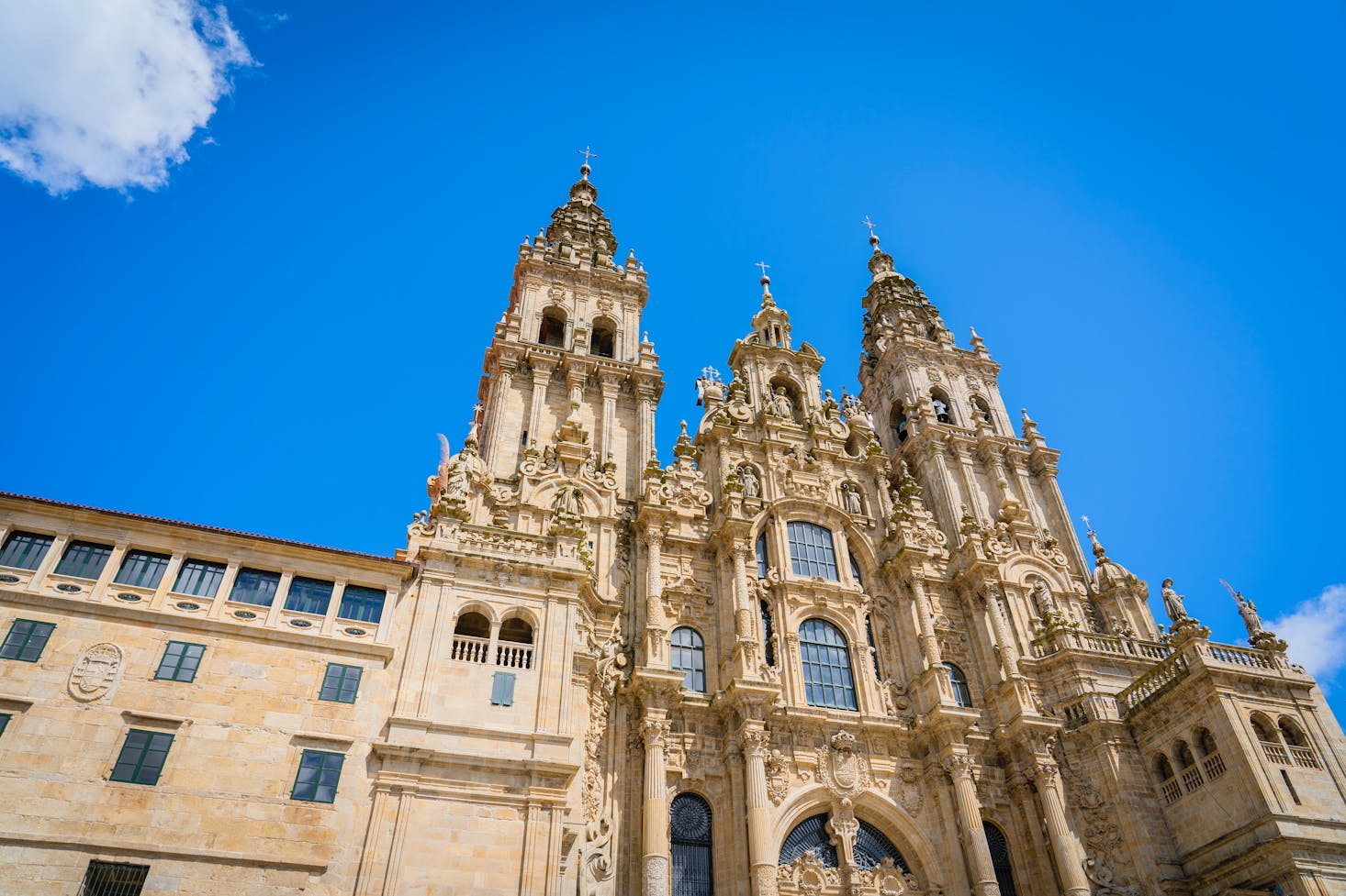 The ornate cathedral in Santiago de Compostela, Spain towers against a blue sky