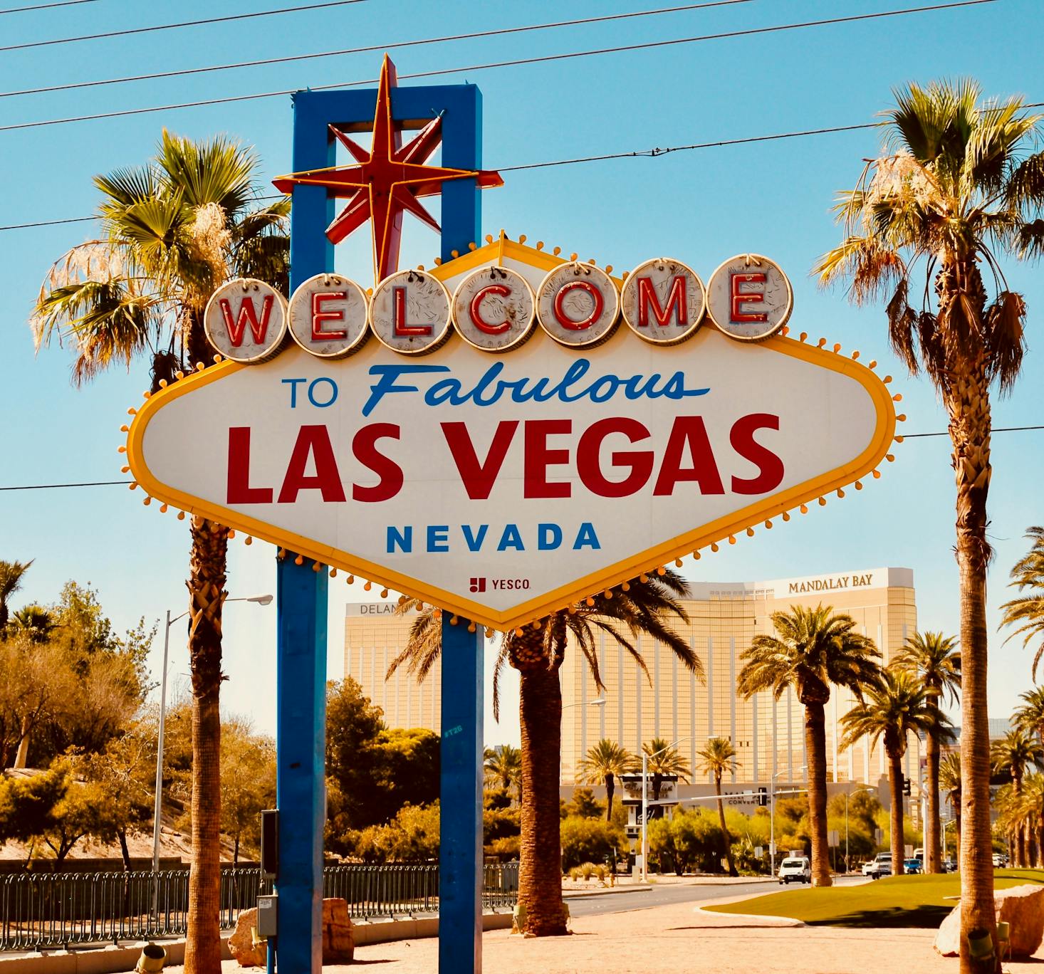 The colorful Welcome to Las Vegas sign greets visitors to the strip lined with palm trees