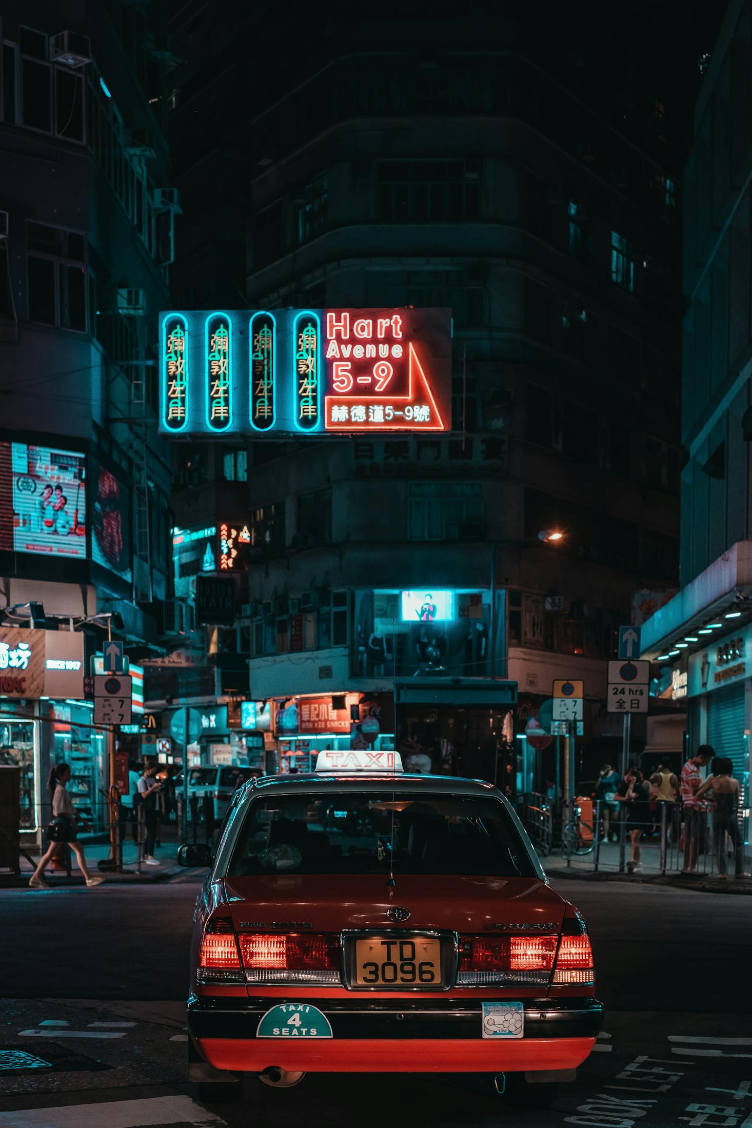 A neon sign in red and blue hangs over a busy street in Tsim Sha Tsui, Hong Kong