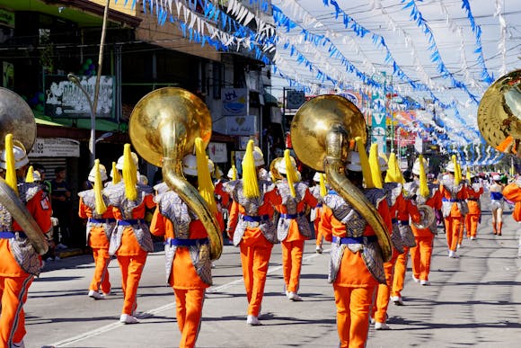 A bright procession filled with spectators and a marching band dressed in orange costumes