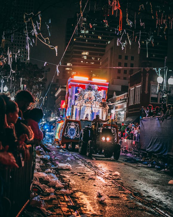 Colorful parade on a snowy, decorated street with an enthusiastic crowd lining the route