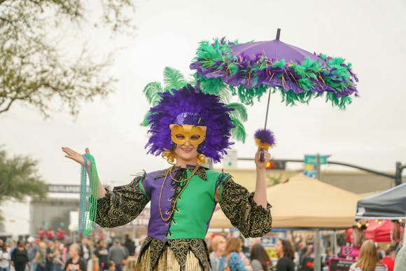 Festival participant wearing a Mardi Gras costume in signature colors of blue, green and yellow.