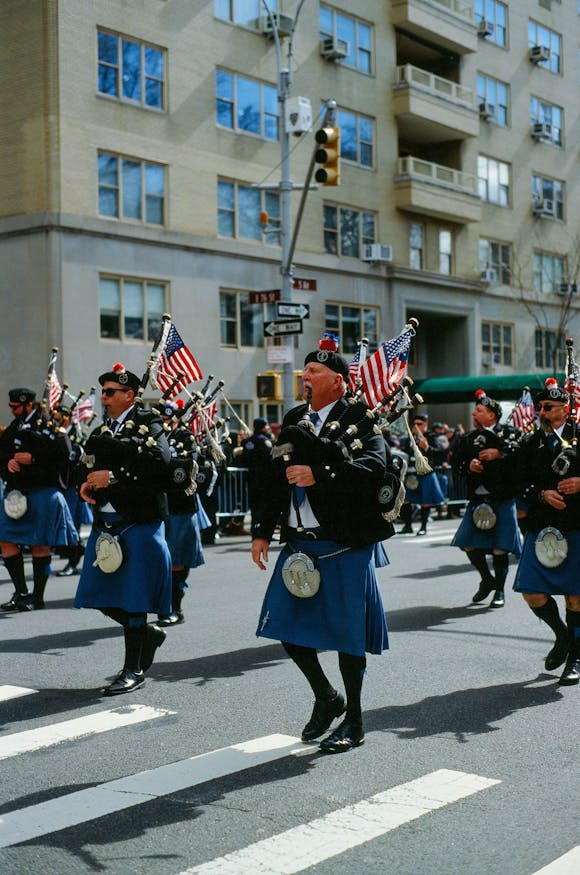 Uniformed participants at the annual St. Patrick's Day Parade marching down the street while playing pipes