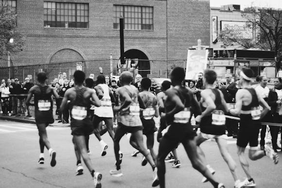 Marathon runners sprinting down the street as an energetic crowd cheers in the background 