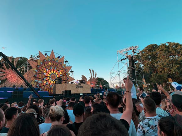 Crowd dancing and listening to a DJ at an outdoor festival