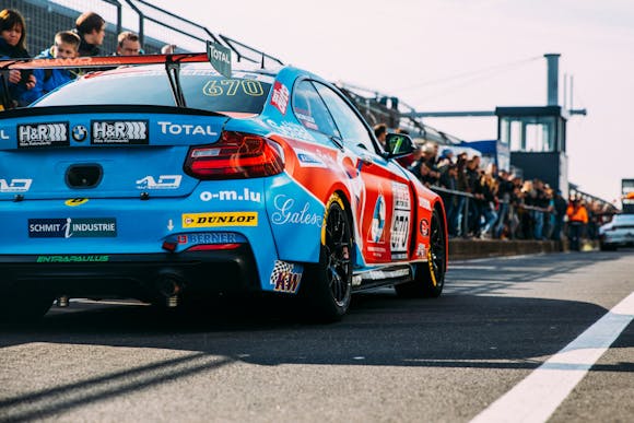 An excited crowd observing a parked racing car