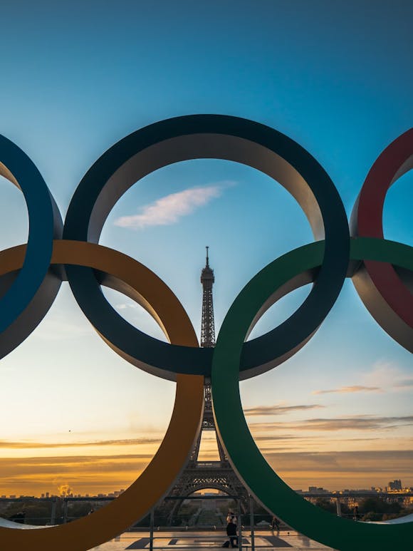 Die olympischen Ringe vor dem Eiffelturm in der Dämmerung