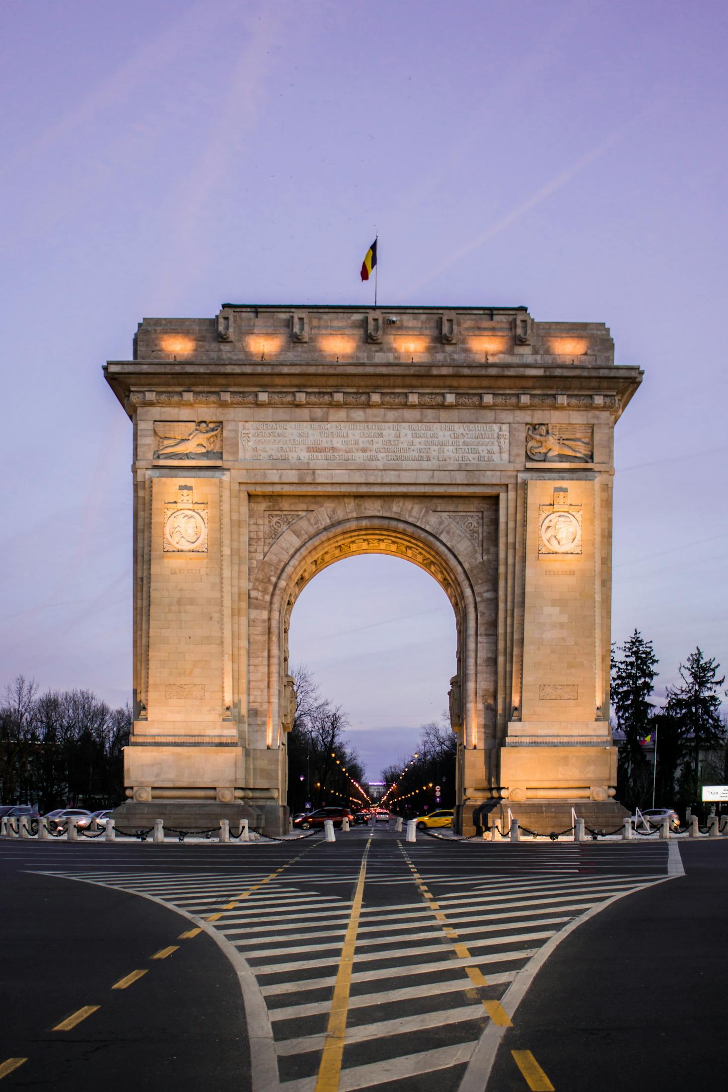 Arcul de Triumf in Bucharest, Romania shown against a purple sky backdrop