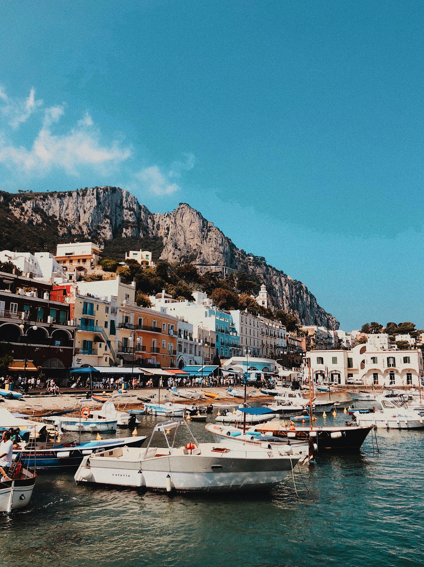 A view of the hilly town of Capri from the water with boats docked