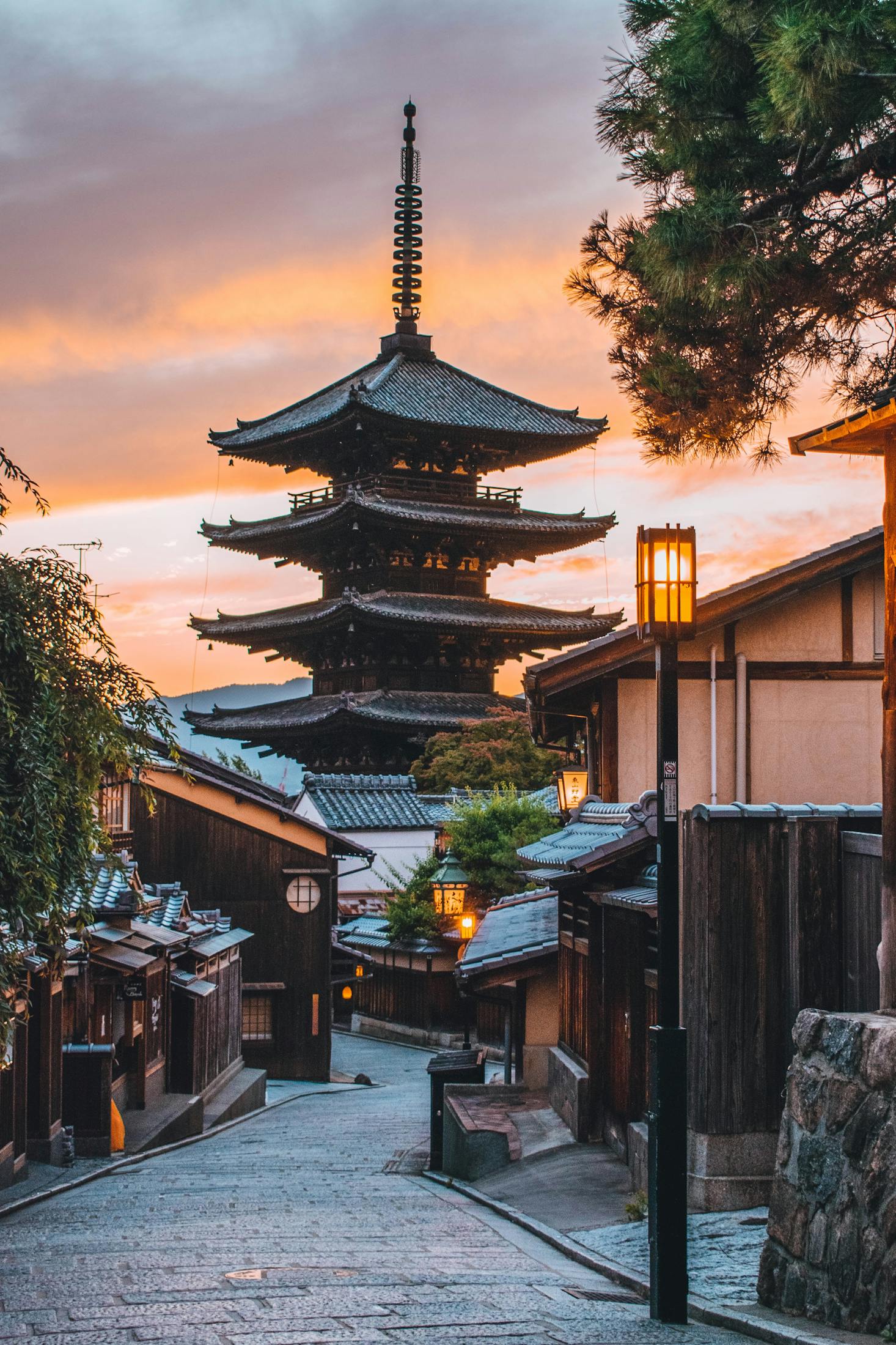 A temple is highlighted in the skyline of a cobblestone lane in Kyoto