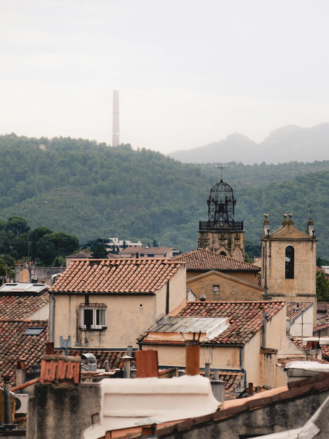 A cloudy day in Aix-en-Provence with brown buildings in front of the hillside