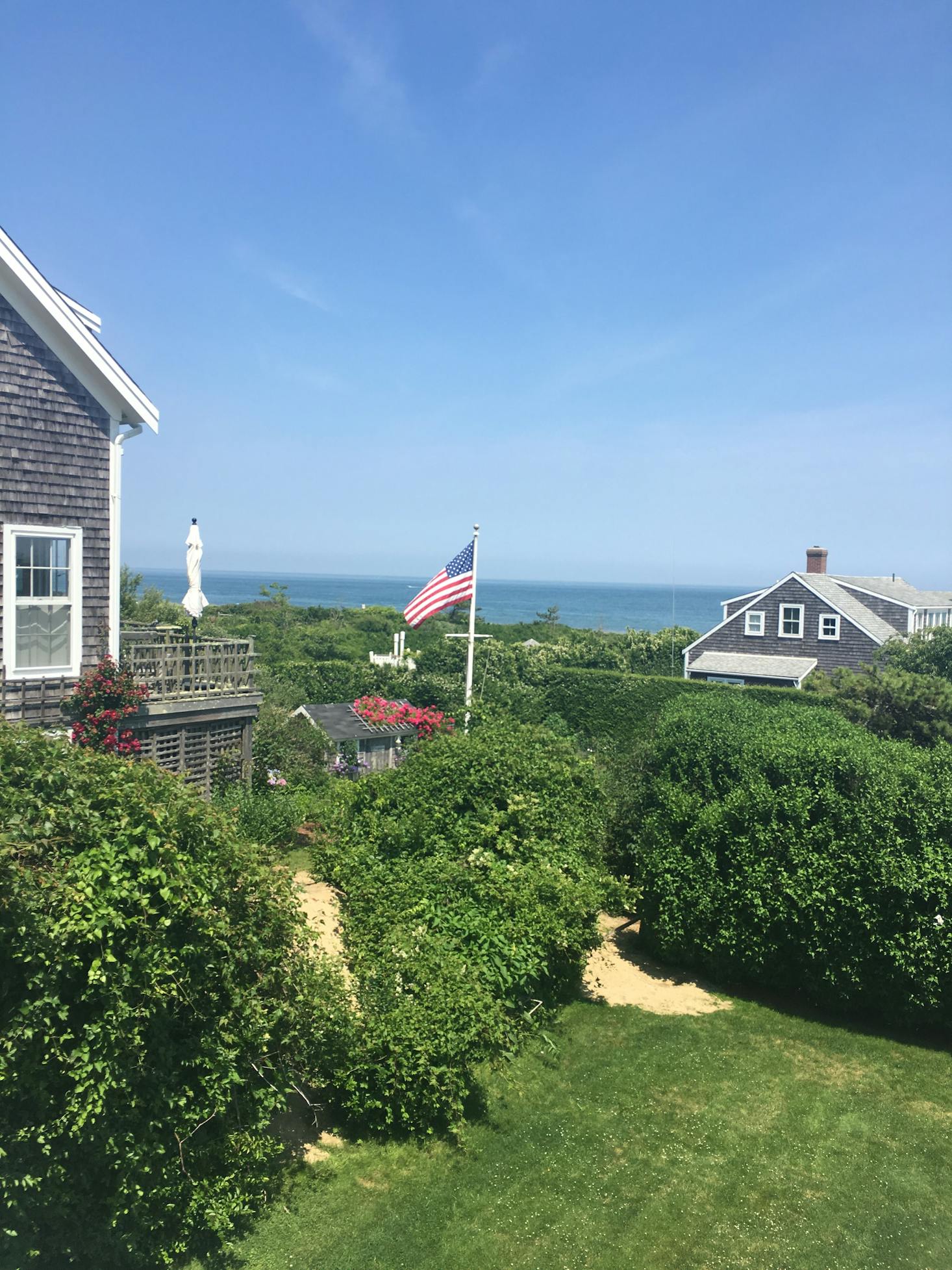 A grey house with American flag in the yard is oceanside in Nantucket, Massachusetts