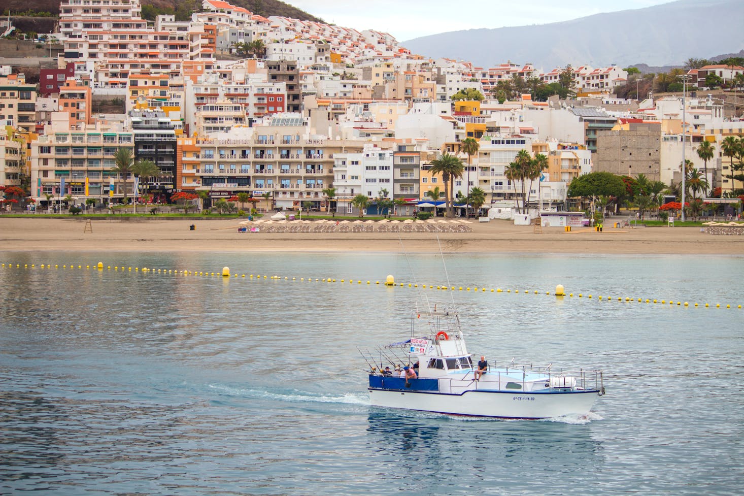 The harbor with a single boat and the city as a backdrop in Los Cristianos, Tenerife