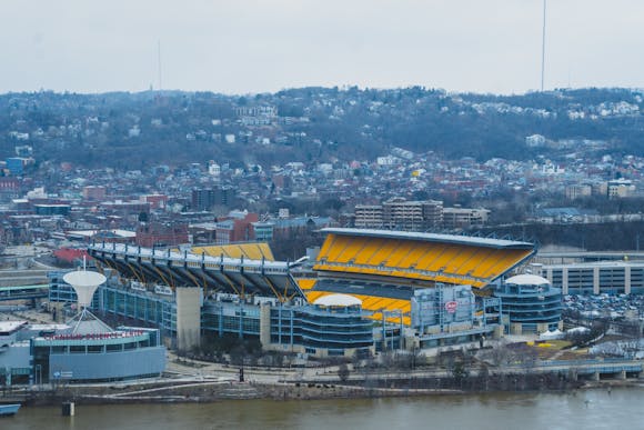 A loaded river barge under the West End bridge on the Ohio river with the  Rivers Casino and Heinz Field in the background in summer time, Pgh, PA, USA  Stock Photo 