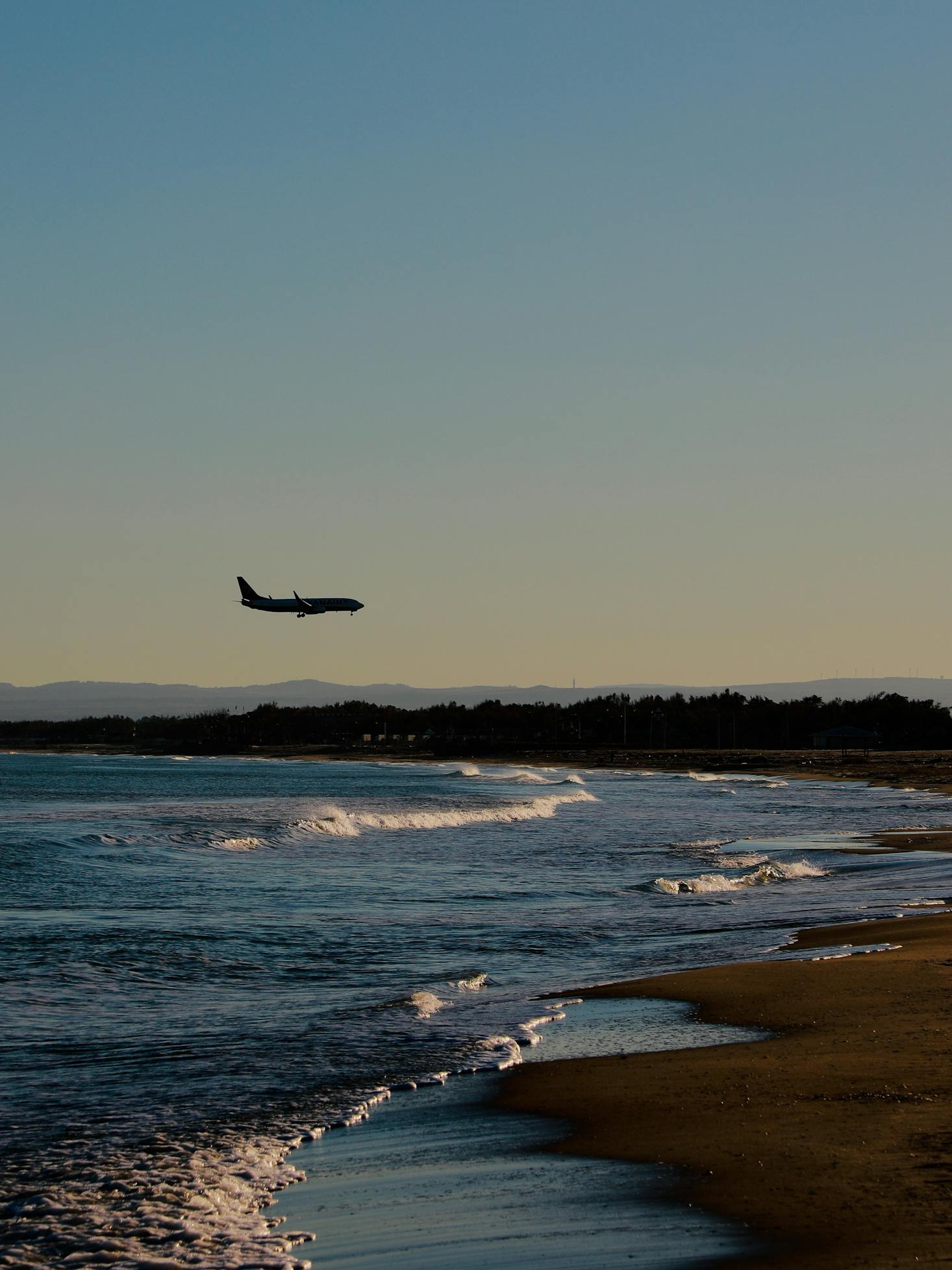 Plane flying over the coast on its way to Catania Airport